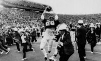 ** FILE ** California's Kevin Moen (26) leaps with the ball in the air after scoring Cal's winning touchdown while the Stanford band runs to get out of his way in Berkeley, Calif., in this Nov. 25, 1982 photo. When the Big Game rolls around each fall, Kevin Moen and Gary Tyrrell can't help being reminded about their roles in the wackiest four seconds in college football history. In 1982, Moen scored for California on the game-ending, five-lateral kickoff return known simply as The Play - and Tyrrell was the Stanford band's trombone player who got leveled by Moen in the end zone. (AP Photo/Oakland Tribune/Robert Stinnett)